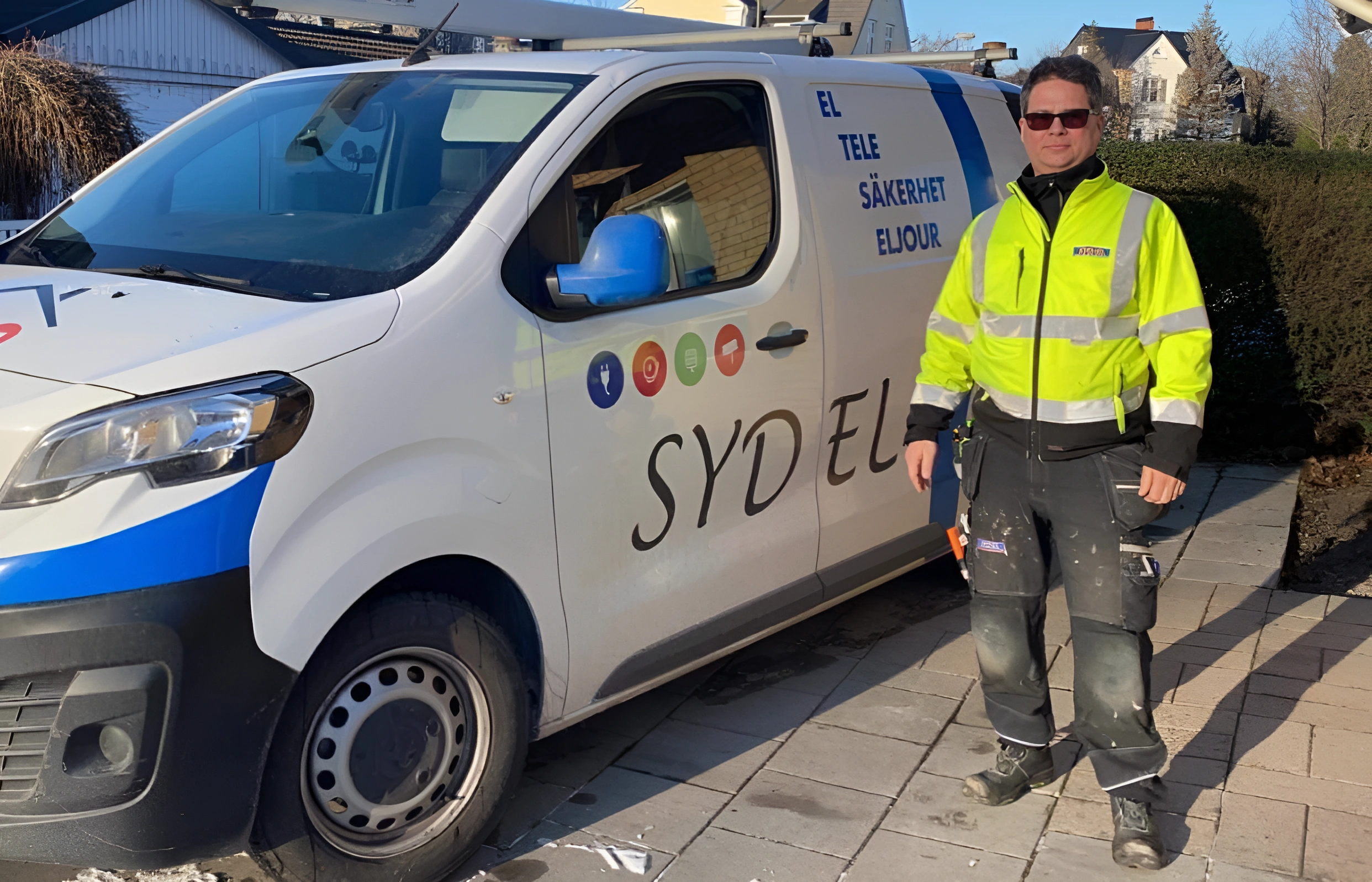 Parkerad cykel på en trottoar vid vattnet i Malmö under kvällsbelysning med gatlyktor och suddiga stadsljus i bakgrunden.