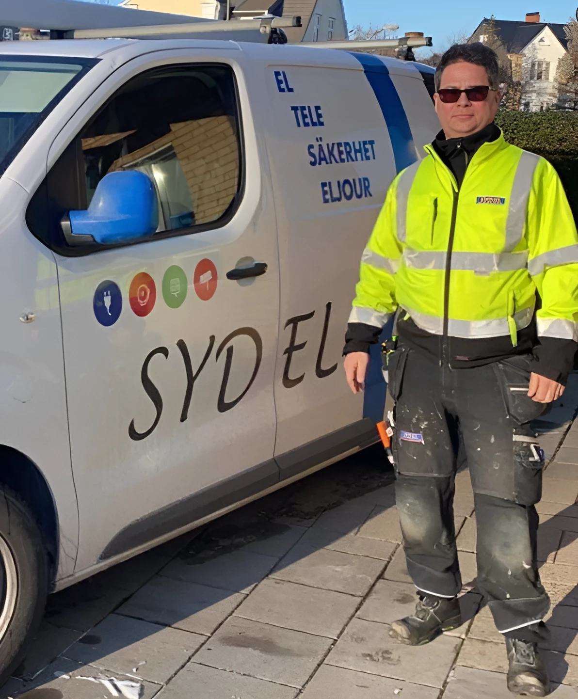 Parkerad cykel på en trottoar vid vattnet i Malmö under kvällsbelysning med gatlyktor och suddiga stadsljus i bakgrunden.